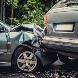 Image of a crashed car that is against the back of a minivan